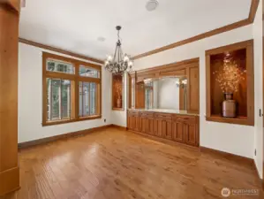Elegant and expansive formal dining space featuring rich wood trim, inset wall alcoves with accent lighting, and a full-length custom built-in buffet with granite countertop and mirrored backsplash — perfect for showcasing heirloom glassware or creating a stylish bar service area.