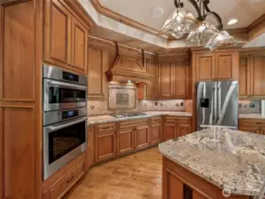 Designed to inspire any home cook — this luxurious kitchen features Bosch double ovens, a gas cooktop with custom wood hood, granite countertops, and a central island. Ample storage, warm wood cabinetry, and views into the great room and yard make this both functional and inviting.