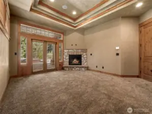 The spacious primary suite offers a cozy gas fireplace, tray ceiling detail, and private patio access leading to the covered hot tub and outdoor fireplace area — creating the ultimate private retreat for morning coffee or evening relaxation.