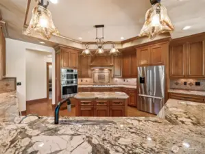 Enjoy a panoramic view of the chef’s kitchen from the raised breakfast bar. Rich granite countertops, pendant lighting, and double ovens complement the space designed for entertaining and effortless cooking.