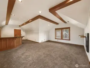 Spacious and open, this upstairs bonus room features vaulted ceilings with beam accents, plush carpet, and room for a home theater, game table, or secondary living space. Connected to the wet bar for easy entertaining.
