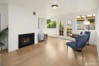 Cozy sitting area off the family room with gas fireplace and French doors leading to the wrap around deck