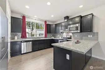 Beautifully designed kitchen with quartz counters, pantry, and light-filled window.