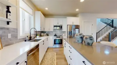 Kitchen with quartz countertops, and stainless-steel appliances.  Refrigerator included in sale.  Image 1 of 2.