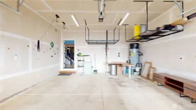 Two car garage with electric opener, bike lift, overhead storage, and 240volt EV plug. Image 1 of 2.