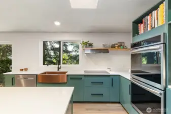 A cook's dream with custom cabinets, tile backsplash, quartz countertops, farmhouse sink, double oven, drawers in the island and new windows bringing in light and to enjoy the view.