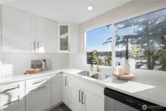 Stylish sink and brushed gold faucet framed by sweeping water views