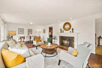 Inviting living room with gas fireplace adjoining formal dining room with walls of windows.
