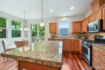 Large island topped with granite and a gas stove.