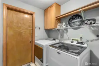 The laundry room with new washer & dryer, hanging bar, shelves & cabinet storage. The door ahead opens to the XL 2-car garage.
