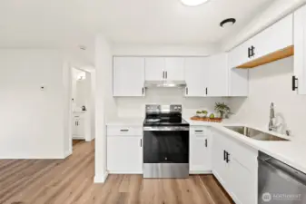 Gleaming Quartz Slab, Crisp White Cabinets, Stainless Appliances, Easy Care LVP Floor