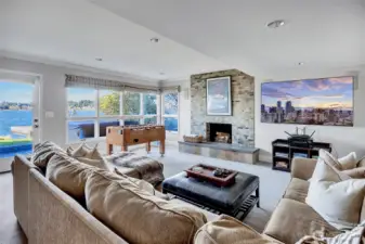 The lower level bonus room is designed for pure enjoyment, perfectly positioned just off the lake for easy access to the outdoors. A cozy fireplace anchors the space, creating the ideal setting for movie nights