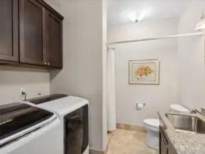 Large laundry room with front-load washer and dryer, ample storage space, and a 3/4 bath.