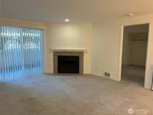 Sunny living room with slider to fenced patio and wood burning fireplace.