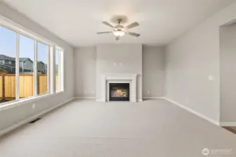 Large living room features a gas fireplace to stay warm on cooler evenings and a ceiling fan to stay comfortable throughout the year.