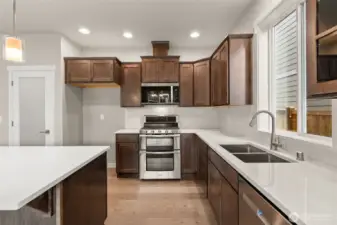 Beautiful stained maple cabinets, quartz counters and full backsplash make this kitchen a stunner! Gas range/double oven is standard! This home also includes a refrigerator.