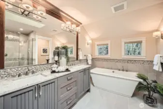 Spa-like primary bath features a spacious curbless shower, freestanding soaking tub, extra-long double vanity, and designer lighting and mirrors for a luxurious retreat.