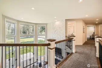 Delightful upper-level catwalk overlooks the grand foyer on one side and the dramatic two-story family room on the other, adding architectural charm and openness.
