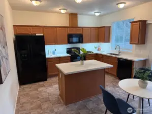 View of kitchen with island/ breakfast bar, new quartz countertops, undermount sink, new faucet and wave-activated undercounter lighting