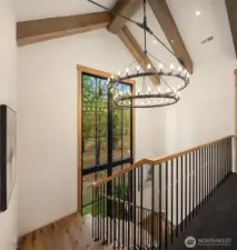 Entryway lights are built into the ceiling beam steel tie-rods, for a unique blend of  structure and elegance. Beams are white oak, with wire brush texture and custom  stain. The bridge is made from solid Doug Fir beams glued and thru bolted together to  create a one piece monolithic plank between the two wings of the upper level.