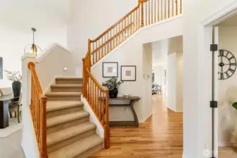 Welcoming entryway with hardwood floors and an elegant staircase leading to the upper level.