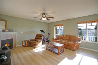 Sunlight fills this warm and welcoming living room, where a cozy fireplace invites you to unwind at the end of the day. The spacious layout and large windows create a comfortable, airy retreat perfect for relaxing evenings or gathering with friends and family.