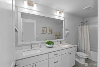 The beautiful finishes continue into the guest bathroom with two vanities, quartz counters and tile floors.