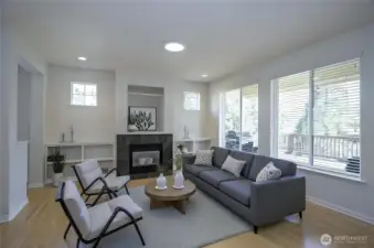Bright and welcoming living area with convenient built-in shelving, expansive windows that fill the space with natural light, and a cozy gas fireplace for added warmth and comfort - virtually staged.