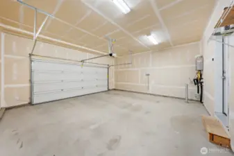 Two car garage with very tall ceilings. Shelving racks stay.