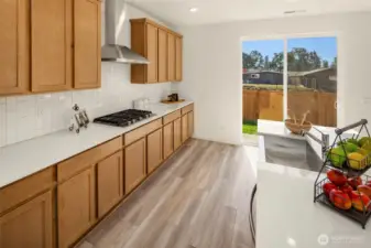 Lovely Quartz counter tops & tiled backsplash, and gas cooktop with vent hood
