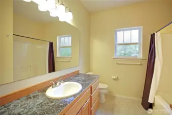 Light & bright guest bathroom offers a tub and plenty of counterspace.