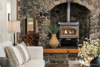 River rock fireplace with wood storage. Efficient wood-burning stove.