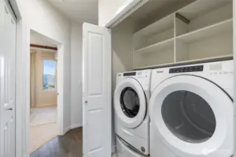 Laundry area with full sized washer and dryer and built in shelving.