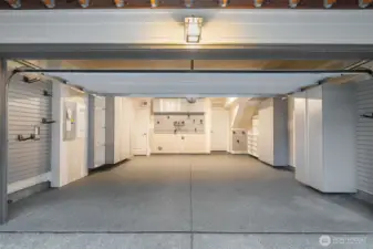 Finished garage with epoxy flooring, custom cabinets, and slatted walls.