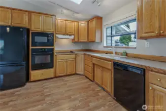 Kitchen has all black appliances, oak cabinets, garden window at sink and skylight for even more natural light.