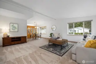 A spacious living room with soaring vaulted ceilings and abundant natural light creates an airy, open, and inviting atmosphere. Fresh new interior paint and flooring throughout home.