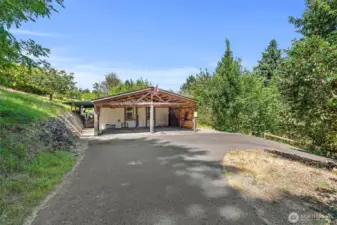Paved driveway with double carport - room for vehicles, tools, and more. It is a free standing structure at the end of the home.