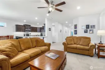 You get a feeling of space and tidiness as you view this wide photo of living room, kitchen, and hallway to the front door.