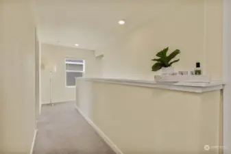 This upstairs hallway is bright and inviting, featuring soft carpeting and recessed lighting. A large window brings in plenty of natural light, creating an open and airy feel. It provides easy access to bedrooms and other living areas, with space for personal décor to make it your own. Functional and simple, it offers a seamless connection throughout the home.