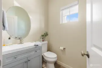 This charming powder room has been completely upgraded, featuring a custom, non-standard vanity that adds a touch of luxury and uniqueness to the space. The sleek design is complemented by soft neutral tones and contemporary finishes. The round mirror adds a stylish touch, while natural light from the window creates a bright and airy feel. Perfectly sized for guests, this newly upgraded bathroom combines practicality with elegant simplicity, making it a standout feature in this thoughtfully designed home.