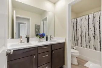 This beautifully appointed bathroom features a modern design with a sleek double vanity, offering ample counter space and storage for all your essentials. The shower is separated by a pull out door.