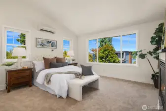 Luxurious primary bedroom features a vaulted ceiling, gas fireplace and partial lake views!