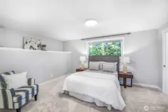 The spacious primary suite is designed as a restful retreat. Soft natural light streams in through the window, enhancing the room’s sense of calm and comfort.