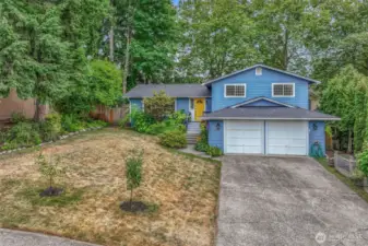 A second view of the property highlights its generous lot size and privacy. Framed by mature trees and greenery, this home offers a peaceful setting while maintaining close proximity to amenities.