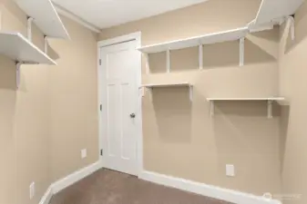 Tidy and functional storage room with built-in shelving. This space is perfect for organizing seasonal items, hobbies, or keeping household essentials easily accessible. More storage located in the closet shown, which leads to under-stair storage.