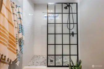 Updated step in shower with glass screen and tile surround.