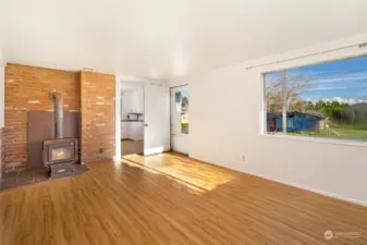 The sunny living room with a cozy wood stove and plenty of natural light from the windows.
