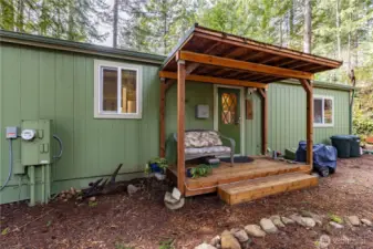 This cozy side entry welcomes you with a charming covered porch. The wood accents add warmth and character, while the seating area creates a relaxing spot to unwind.