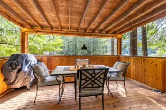 This inviting covered deck is a perfect all-weather retreat, surrounded by trees. With space for outdoor dining