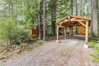 covered parking surrounded by the natural beauty of the Pacific Northwest. The gravel driveway provides additional parking space, while the nearby powered shed offers extra storage or workshop potential